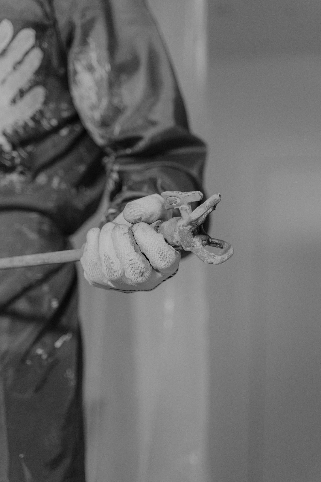 Monochrome photo featuring a worker's hand gripping a wrench, Monochrome photo featuring a worker's hand gripping a wrench, symbolizing construction.
